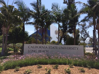Eine blaue Pyramide hinter Palmen und einem California State University Long Beach Schild