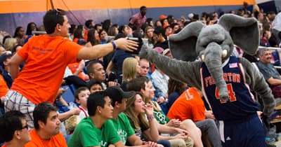 Eine Turnhalle mit Studenten und einem Elefant als Maskottchen