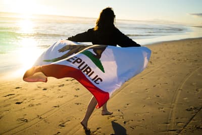 Mädchen mit Kalifornien-Flagge am Strand