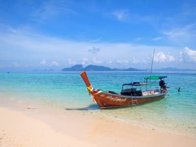 Motorboot an thailändischem Strand mit sehr klarem Wasser