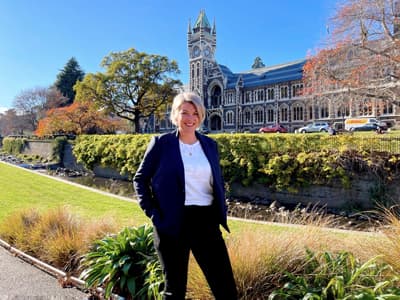 Teri Higgins ist blond und steht in einem blauen Blazer vor der University of Otago